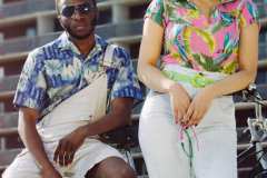 Anicia, wearing a 90's pink tropical shirt, 80's washed out denim patched shorts, lime green vinyl belt. Tahir, wearing blue 70's Hawaiian shirt and overall shorts.