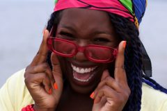 Josie is wearing an 80's colour-blocked scarf around her head, 90's inspired sun glasses, and wood bangles from the shop.