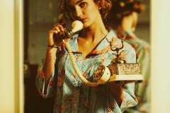 Grace, wearing an 80's striped/floral house dress, talking on vintage rotary phone.