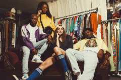 Tahir, wearing 80's purple striped windbreaker, Adidas high-top sneakers. Diane, wearing yellow Nike jersey, Esprit shoulder bag. Andrea, wearing navy sport jersey, knee-high socks. Franklin, wearing 80's denim jeans, USA crew neck sweater, yellow 90's windbreaker.