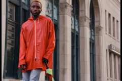 Tahir, wearing 90's red vinyl rain coat, 80's Adidas high-top sneakers.